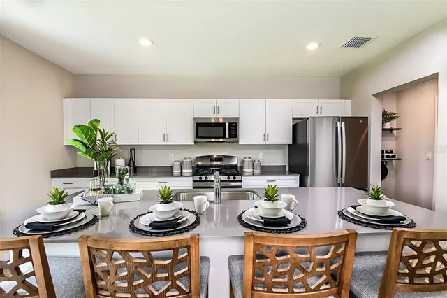 a kitchen with stainless steel appliances a stove a sink and a dining table
