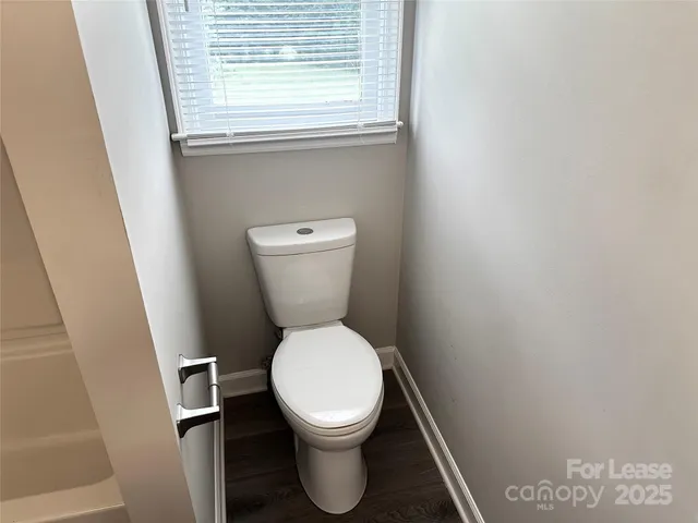a white toilet sitting in a bathroom next to a window