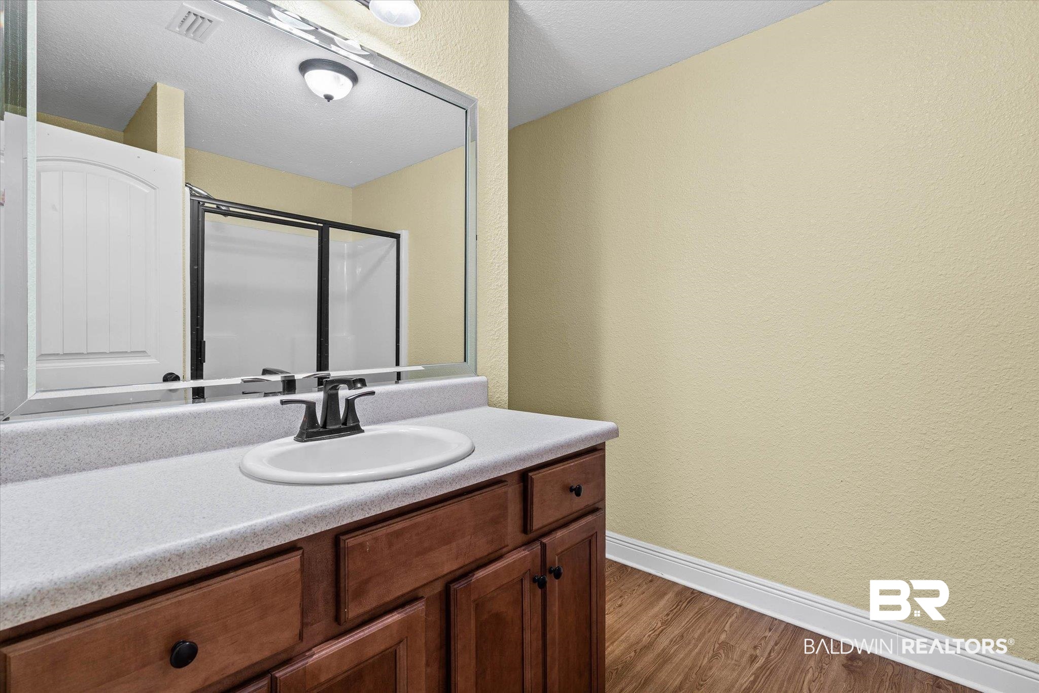 101 Washington Boulevard Foley, AL 36535 - Photo 15 of 32 Full bathroom with vanity, a textured wall, dark wood-style flooring, a shower stall, and a textured ceiling