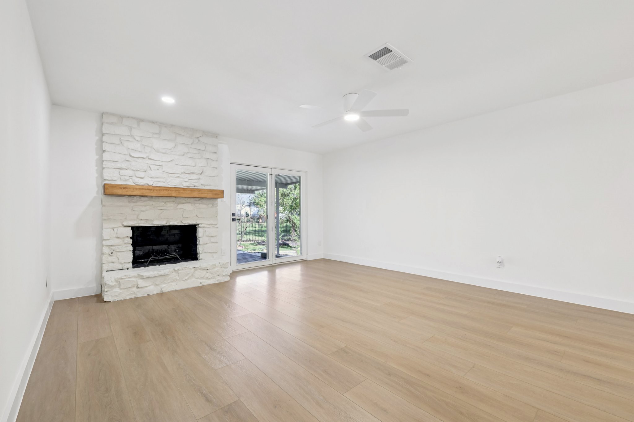8214 Kearsarge Drive Austin, TX 78745 - Photo 10 of 40 Unfurnished living room featuring light wood-style floors, a stone fireplace, and a ceiling fan