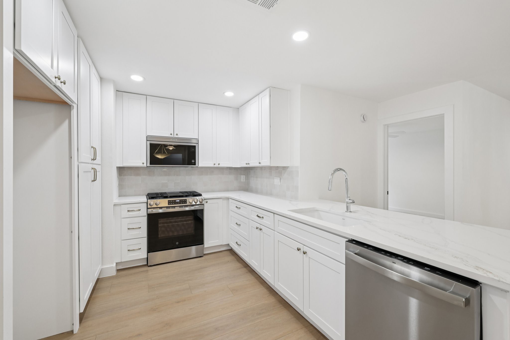 8214 Kearsarge Drive Austin, TX 78745 - Photo 17 of 40 Kitchen featuring stainless steel appliances, white cabinetry, light stone countertops, light wood finished floors, and recessed lighting