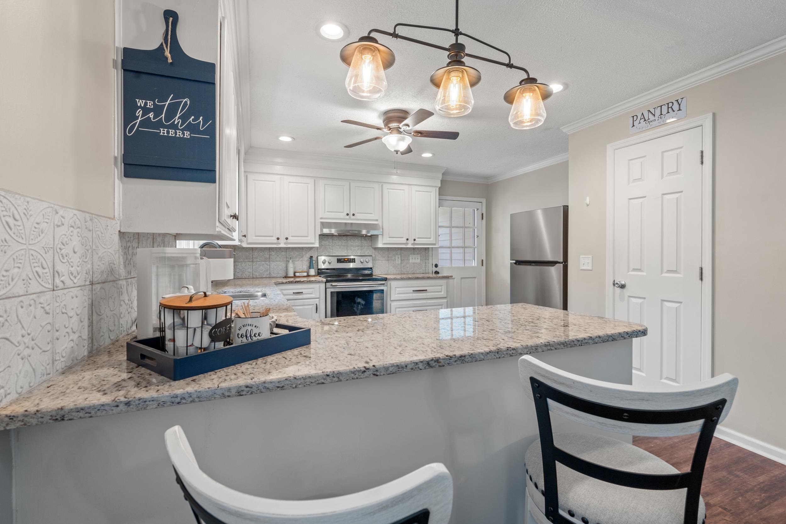 208 Bethea Street Latta, SC 29565 - Photo 9 of 36 Kitchen featuring light stone counters, a peninsula, a breakfast bar, ornamental molding, and stainless steel appliances