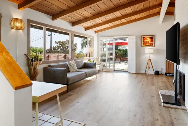 a living room with furniture a flat screen tv and floor to ceiling window