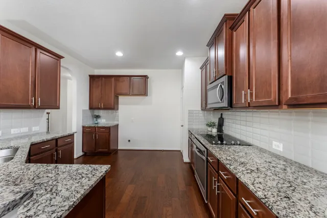 a kitchen with granite countertop wooden cabinets and stainless steel appliances