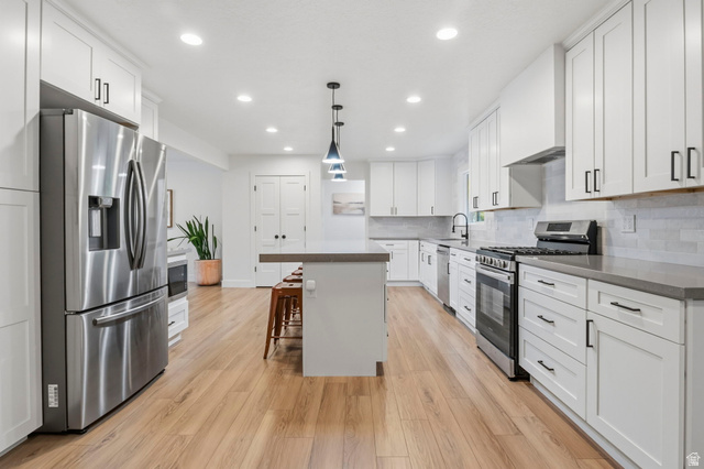 4150 Dover Lane Provo, UT 84604 - Photo 12 of 44 Spacious kitchen featuring extensive white cabinetry, stainless steel appliances, wood-finish flooring, a central island, and recessed lighting