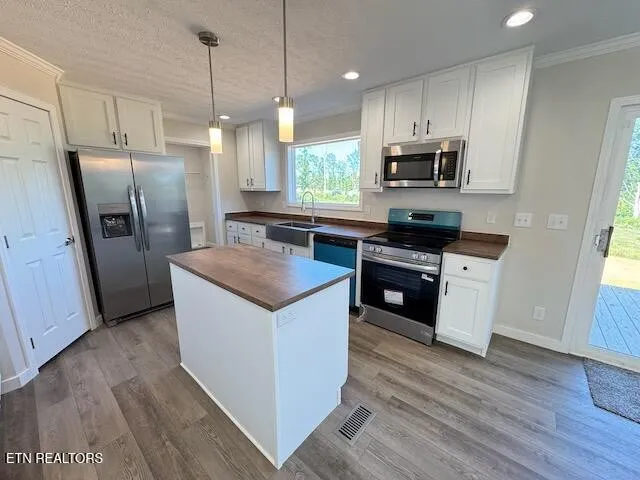 a kitchen with stainless steel appliances a sink a stove a refrigerator and cabinets