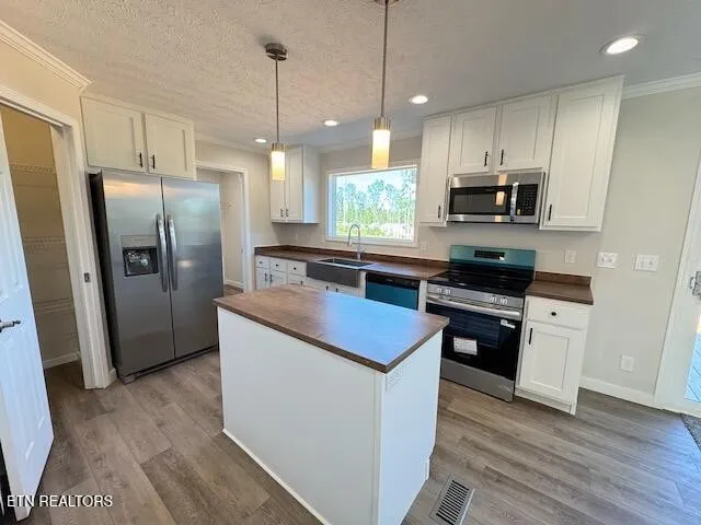 a kitchen with stainless steel appliances kitchen island granite countertop a refrigerator a sink a stove a microwave and wooden floors
