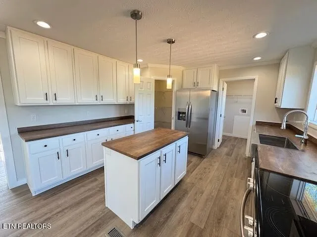 a kitchen with stainless steel appliances granite countertop a stove a refrigerator a sink and white cabinets