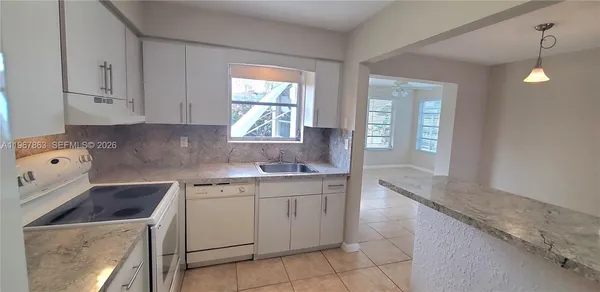 a kitchen that has a sink a stove and cabinets