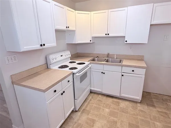 a kitchen with granite countertop a sink a stove and cabinets