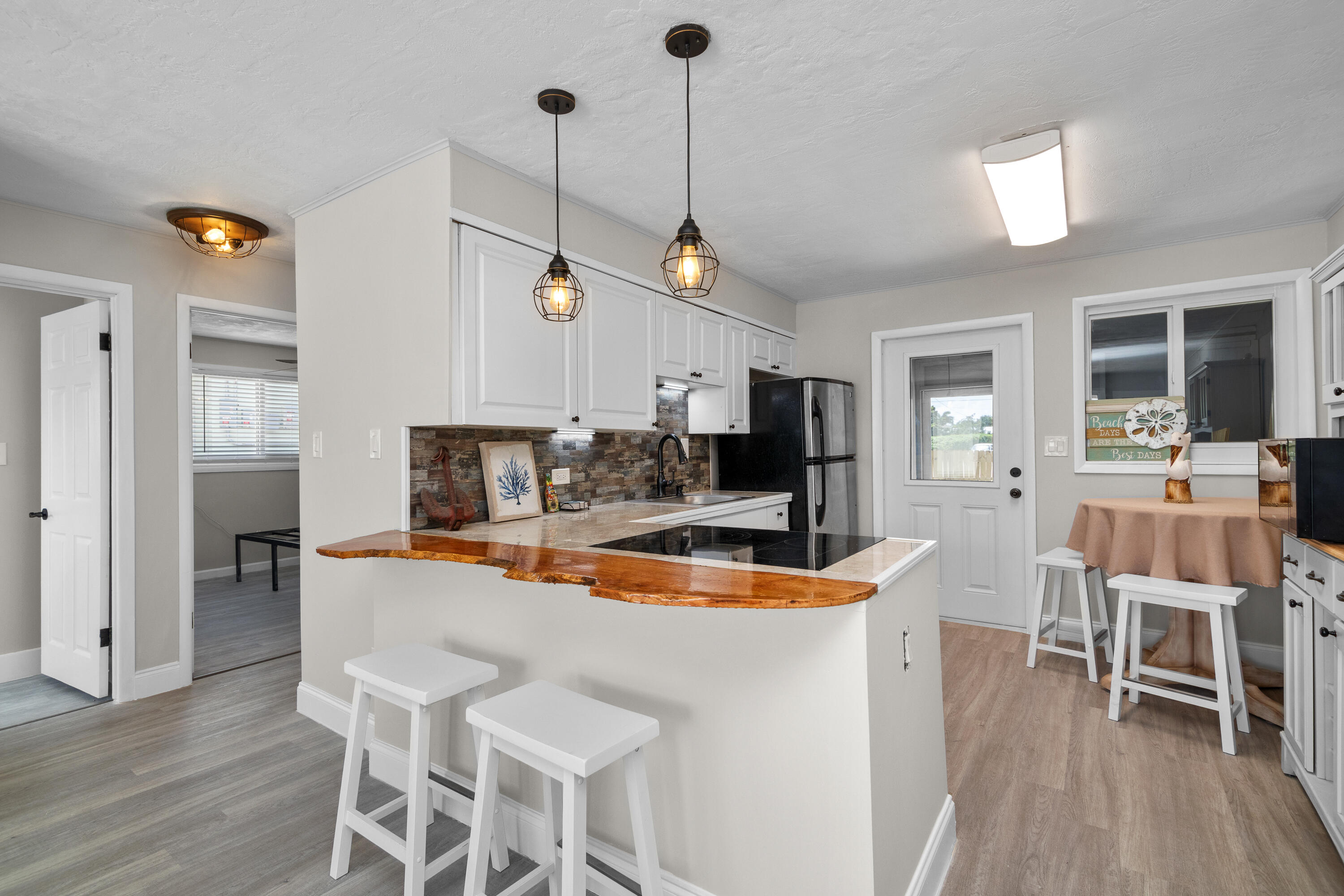 10873 7th Ave Gulf Marathon, FL 33050 - Photo 13 of 25 a dining room with wooden floor a chandelier a wooden table and chairs