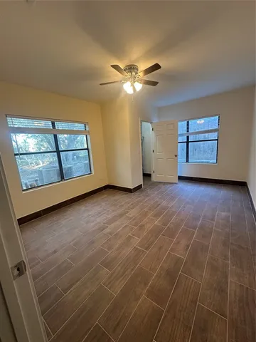 an empty room with windows and ceiling fan