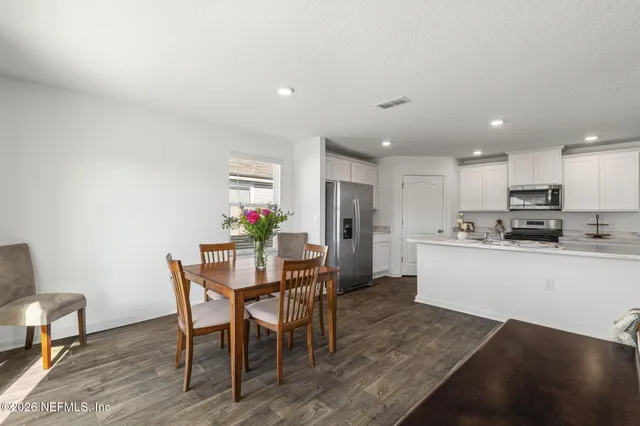 a kitchen with a dining table chairs and refrigerator