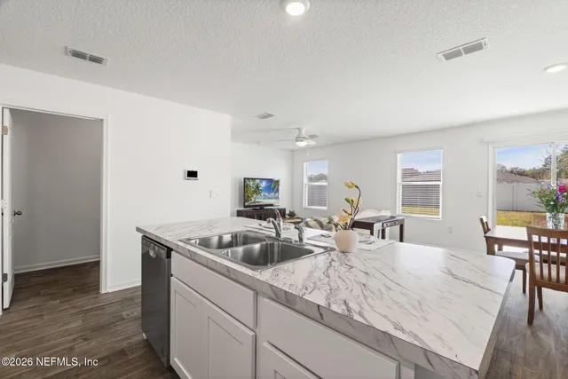 a kitchen with granite countertop a sink and white cabinets