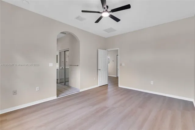 an empty room with wooden floor and a ceiling fan