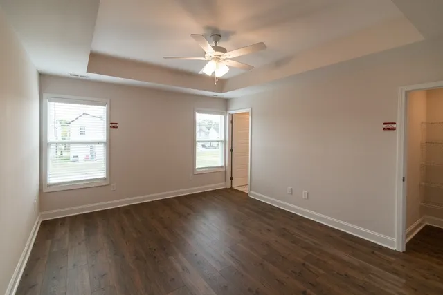 an empty room with wooden floor fan and windows