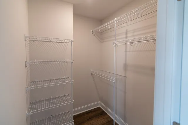 an empty room with wooden floor and fan