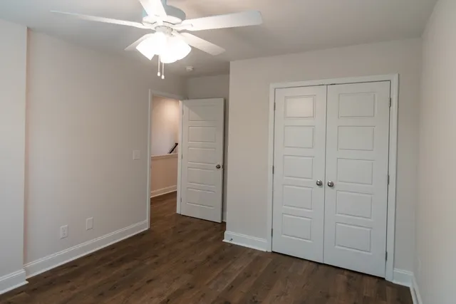 an empty room with wooden floor and chandelier fan