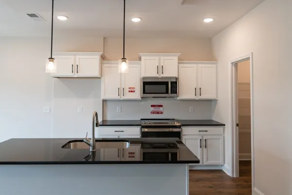 a kitchen with stainless steel appliances granite countertop a stove a sink and a microwave