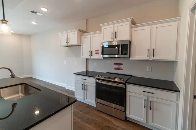 a kitchen with stainless steel appliances granite countertop a sink stove and microwave