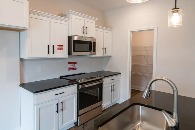 a kitchen with stainless steel appliances granite countertop a stove a microwave a sink and cabinets