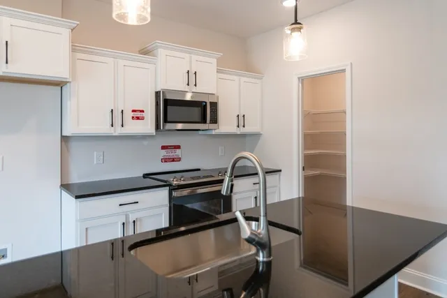 a kitchen with stainless steel appliances a stove a sink a microwave a refrigerator and cabinets