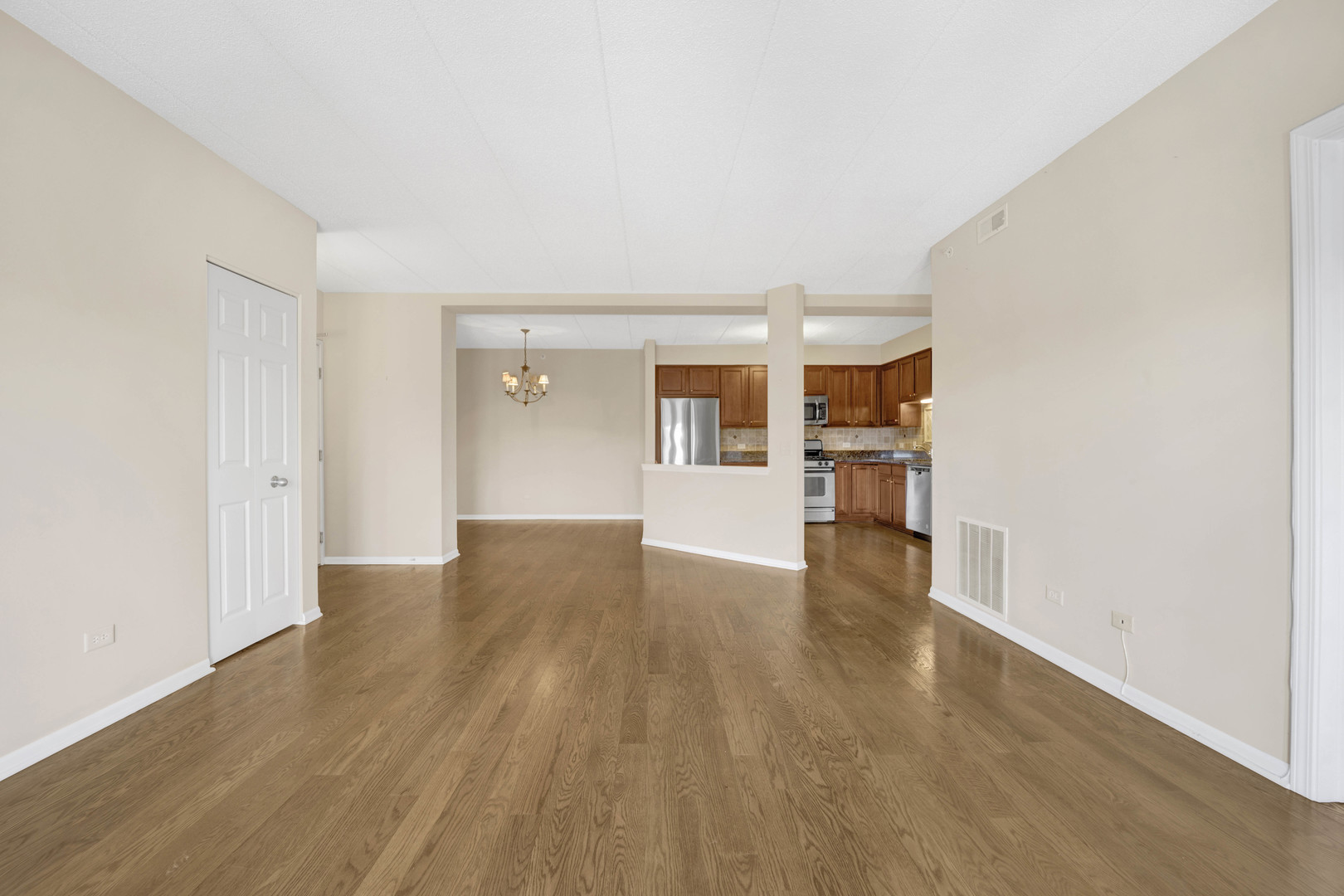 201 West Brush Hill Road, Unit 203 Elmhurst, IL 60126 - Photo 5 of 24 a view of empty room with wooden floor and kitchen