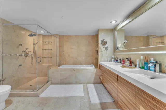 a bathroom with a bathtub shower sink mirror and toilet
