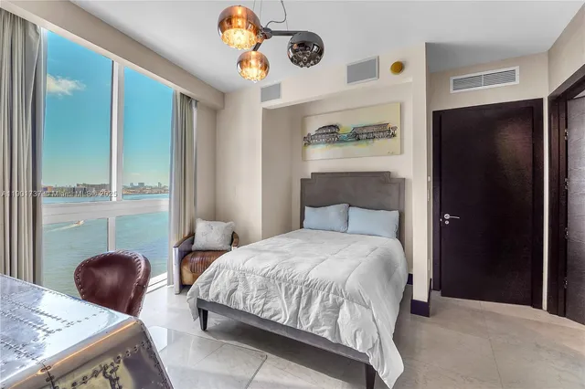 a bedroom with a bed a chandelier and dresser