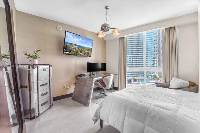 a bedroom with furniture a window and a flat screen tv