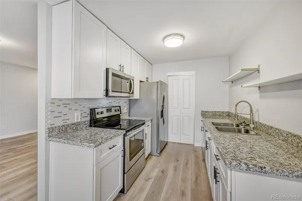 a kitchen with stainless steel appliances granite countertop a sink stove microwave and refrigerator