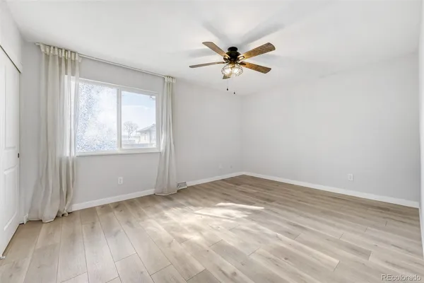 an empty room with windows and fan