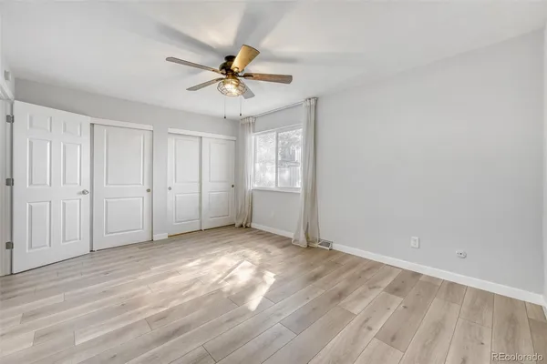 an empty room with windows and fan