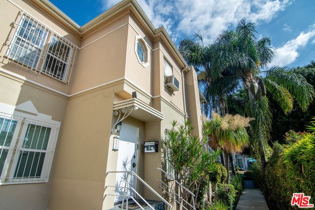 a front view of a multi story residential apartment building with yard and entryway