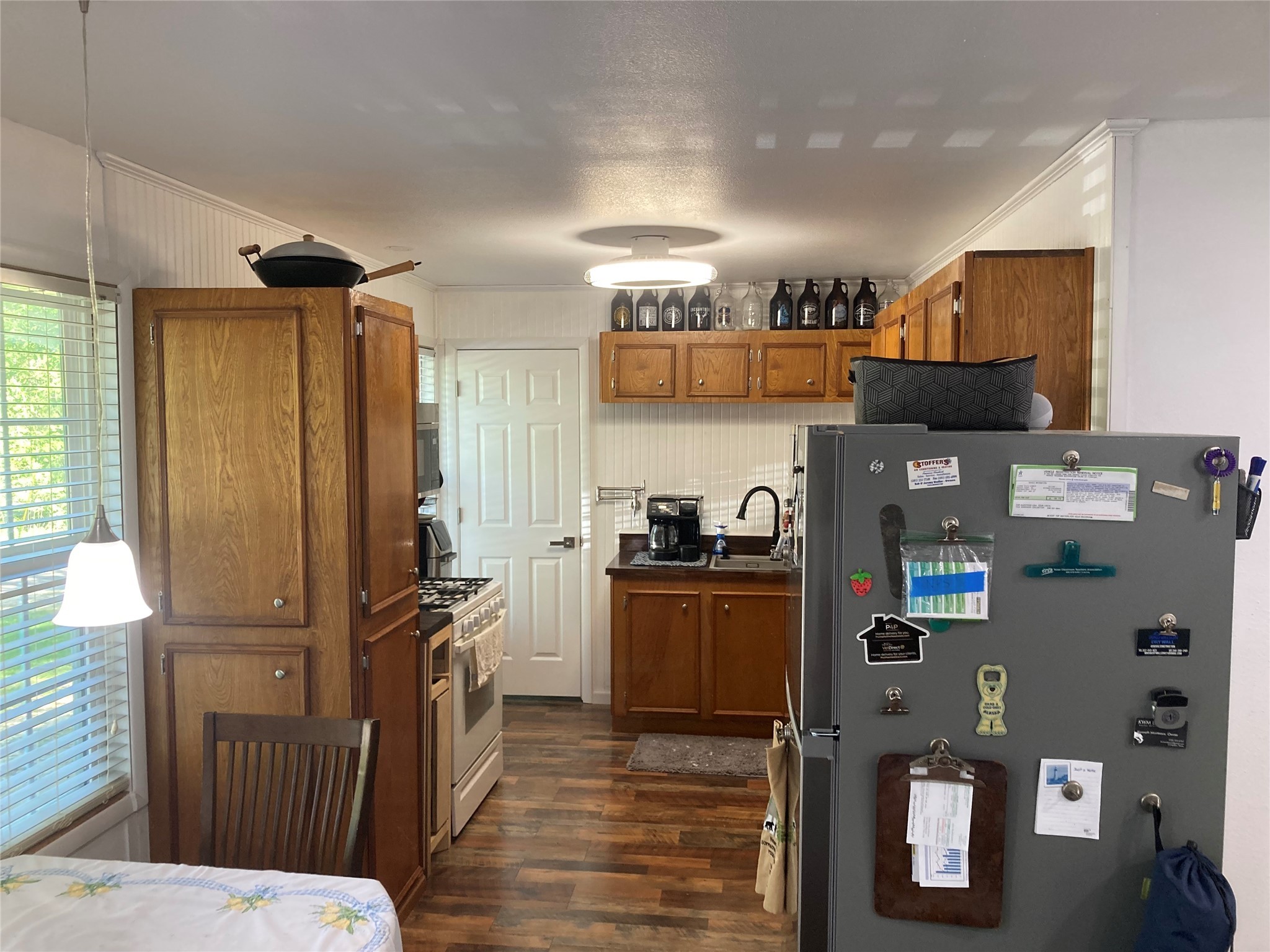 142 Walnut Ridge Livingston, TX 77351 - Photo 4 of 36 This cozy kitchen features wooden cabinets, a gas stove, and a stainless steel refrigerator. It has a warm, inviting atmosphere with ample natural light from the window and a small dining area to the side.