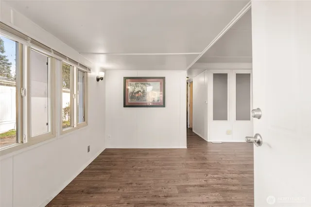 a view of an empty room with wooden floor and a window