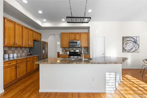 a kitchen with kitchen island granite countertop a stove a sink a window and cabinets
