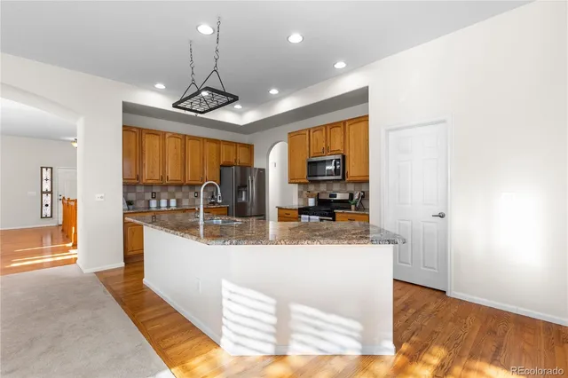 a large kitchen with stainless steel appliances granite countertop a sink a stove counter space and cabinets