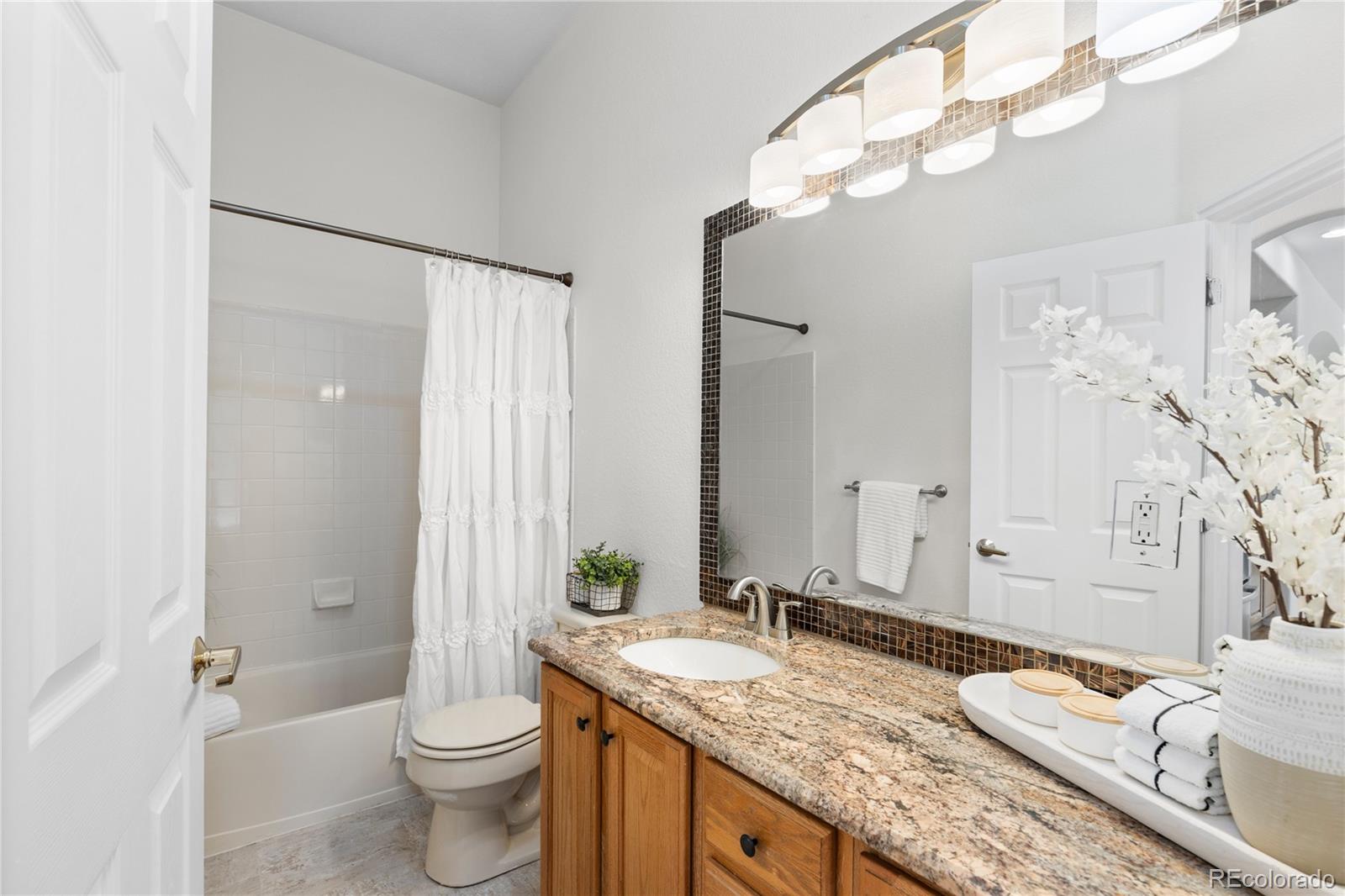 8166 Wetherill Circle Castle Pines, CO 80108 - Photo 24 of 49 a bathroom with a granite countertop sink and a mirror