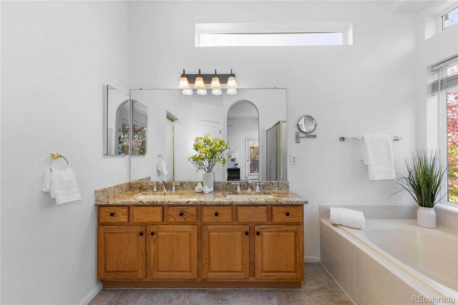 8166 Wetherill Circle Castle Pines, CO 80108 - Photo 31 of 49 a bathroom with a granite countertop sink a mirror and a bathtub