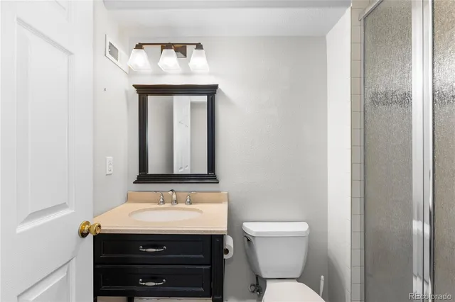 a bathroom with a granite countertop sink toilet and mirror