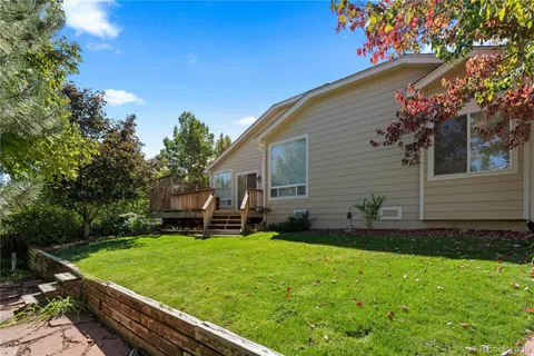 a backyard of a house with table and chairs plants and large tree