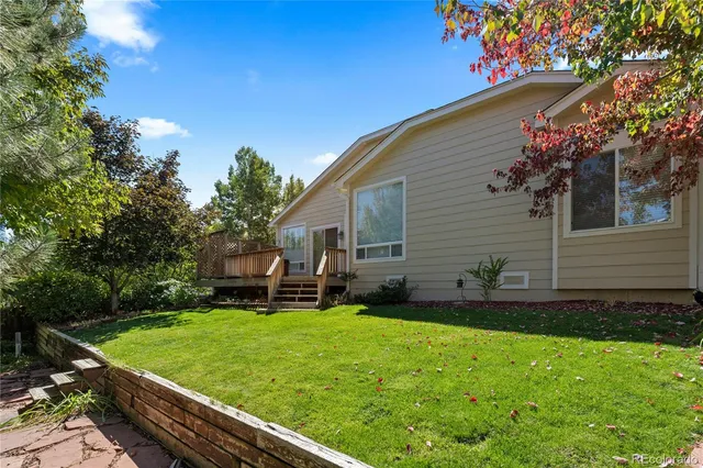 a backyard of a house with table and chairs plants and large tree