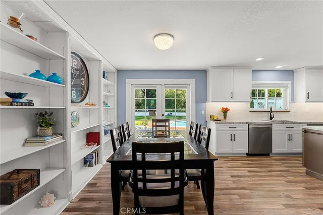 a kitchen with granite countertop a table chairs a sink dishwasher stove and cabinets with wooden floor