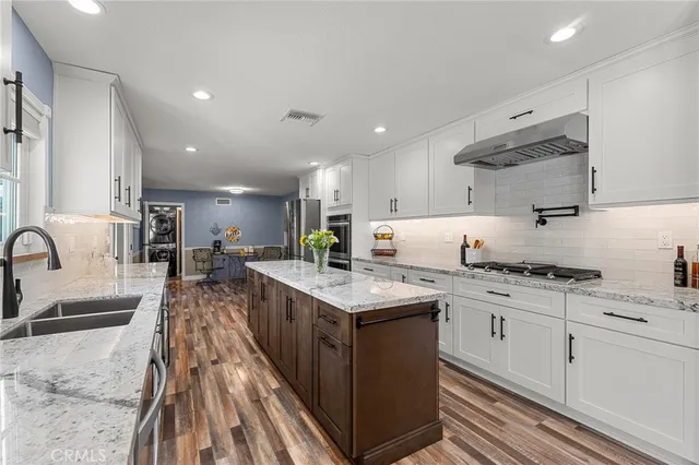 a kitchen with stainless steel appliances granite countertop a stove top oven a sink a counter space and cabinets