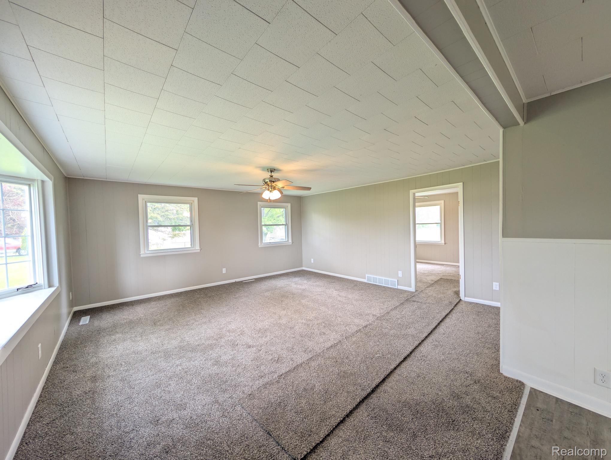 7032 Neff Road Mount Morris, MI 48458 - Photo 13 of 20 Spare room featuring ceiling fan, carpet floors, and wood walls