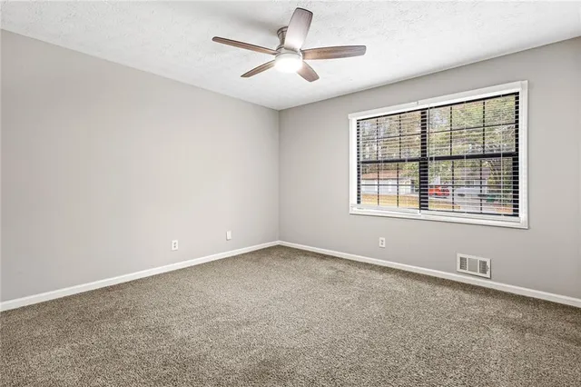 an empty room with windows and ceiling fan