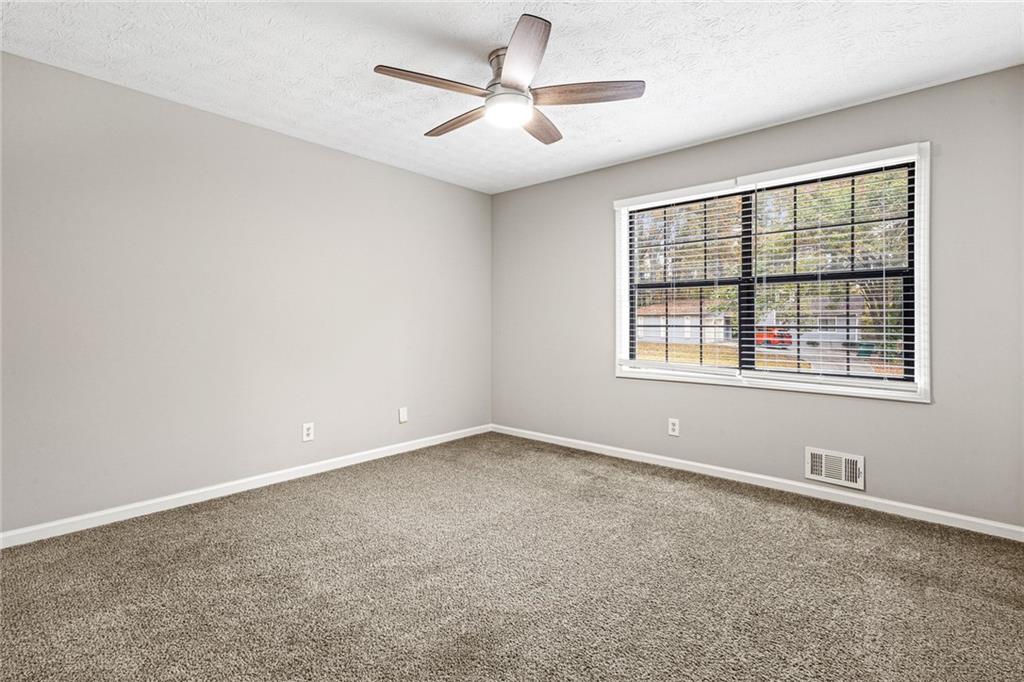 1735 Charmeth Road Lithonia, GA 30058 - Photo 13 of 27 an empty room with windows and ceiling fan