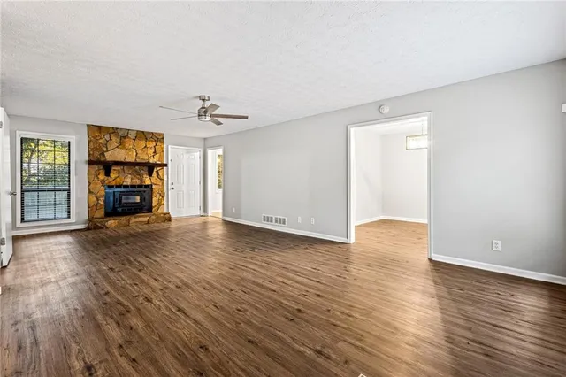 an empty room with wooden floor fireplace and windows