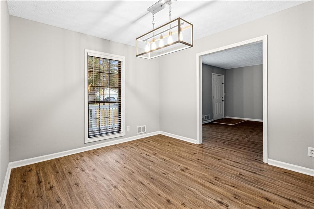 1735 Charmeth Road Lithonia, GA 30058 - Photo 6 of 27 an empty room with wooden floor cabinet and windows